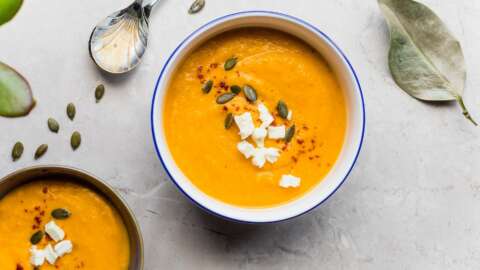 Lunchbox: Schüssel mit einer leuchtend orangen Suppe, mit Kürbiskernen darin.
