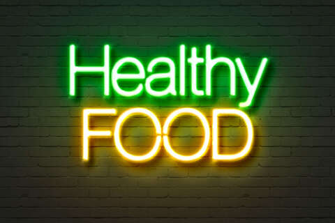 Clean Eating: Neonschild mit Aufschrift Healthy food auf einer Ziegelsteinwand