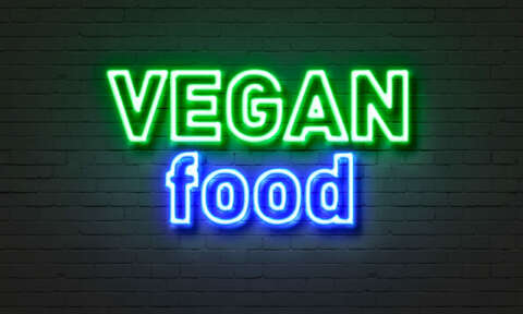 Vegan: Neonschild mit Aufschrift Vegan food auf einer Ziegelsteinwand