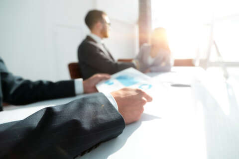 Zwei Männer sitzen im gegenlicht in einem Büro.