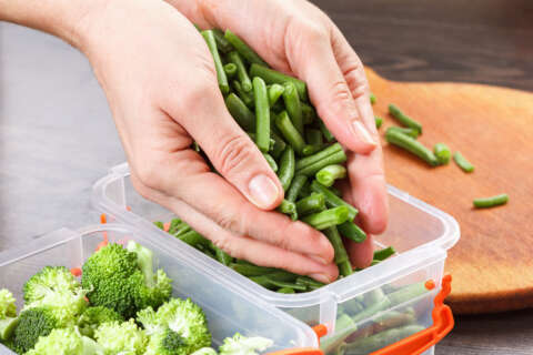 Klein geschnittene Bohnen werden in eine Gefrierbox per Hand gefüllt. Eine Box mit Brokkoli steht daneben