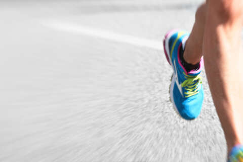 Marathon Planung: Läuferbeine mit bunten Turmschuhen auf Asphaltstraße