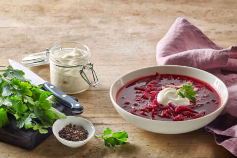 Typisch für die russische Küche: Teller mit Rote Beete-Suppe auf einem Holztisch