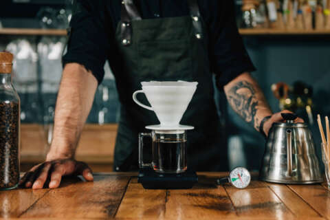 Filterkaffee: Ein Mann brüht Kaffee mit einem Filter auf, Daneben steht eine Kanne und liegt ein Thermometer.
