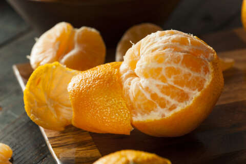 Zero-Waste: Mandarine auf einem Holzbrett, die zur Hälfte geschält ist