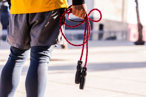 Seilspringen: Ein Mann steht auf einem Platz und hat ein rotes Seil in der Hand