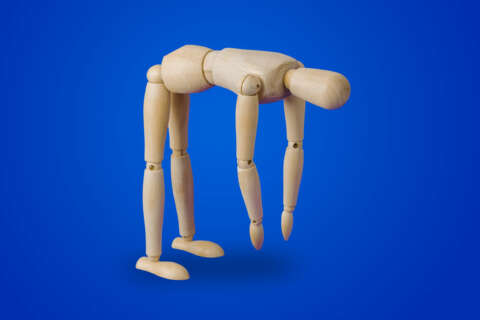 Rückenschmerzen: Eine Holzfigur macht eine Vorwärtsbeuge