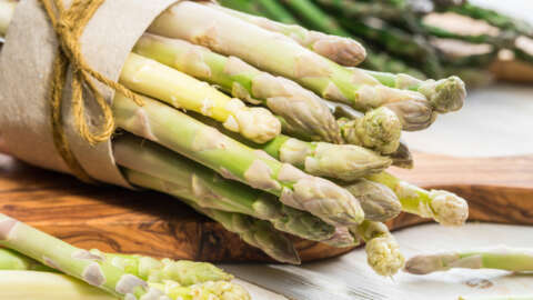 Spargel: Jeweils ein Bund weißer und grüner Spargel liegen auf einem Holzbrett