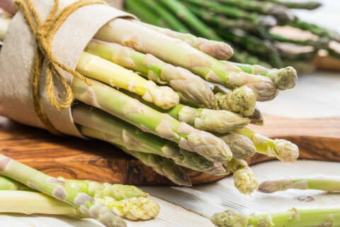 Spargel: Jeweils ein Bund weißer und grüner Spargel liegen auf einem Holzbrett