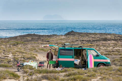 Outdoor-Typ: Ein Mann und eine Frau campen in einem Van an einer Küste
