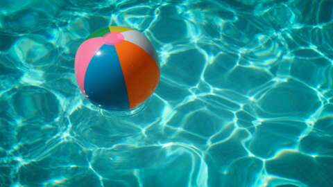 Endlich Sommer: Ein Beachball schwimmt in einem blauen Pool