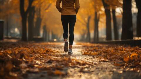 Healthy Herbst: Joggerin läuft durch Laub.