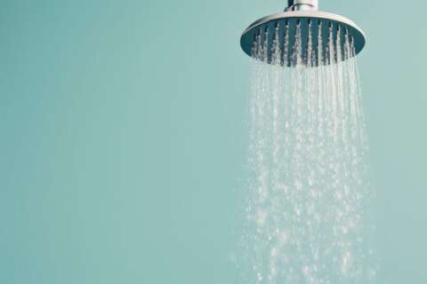 Wechseldusche: Duschkopf, aus dem Wasser läuft.